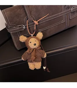 Detailed close-up of a brown knitted teddy bear charm on a textured leather tote bag