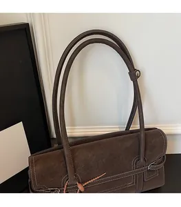 Detail of dark brown suede underarm bag featuring white contrast stitching and thin straps