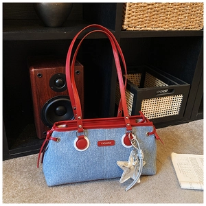 Détail du sac bandoulière en denim bleu avec bordure rouge, étiquette et étoile argentée