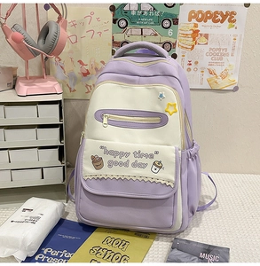 Detail of cute purple and beige school backpack with cartoon patterns and star pendant