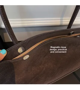Detail view of the brown matte leather tote bag featuring multiple magnetic closure buckles