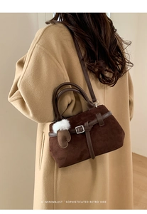 Détail d'un sac cabas rétro en daim marron avec charm gant sur un long manteau