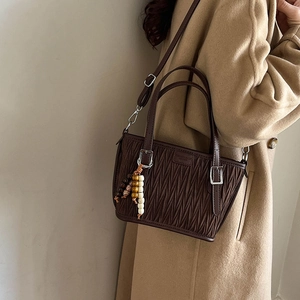 Detail of dark brown pleated texture bucket bag with wooden beads and silver hardware