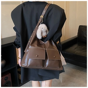 Detailed view of deep brown faux leather tote with two front pockets and plush rabbit charm