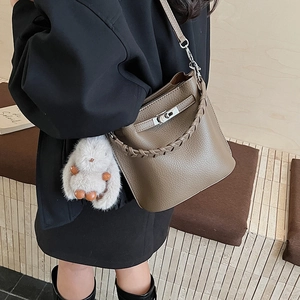 Détail du sac seau en cuir taupe avec fermoir métallique Kelly et poignée tressée