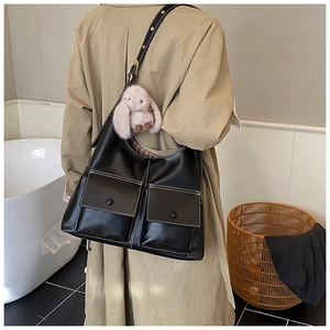 Detail of black faux leather tote featuring dual utility pockets and contrast stitching