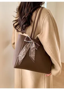 Detail of dark brown tote bag with decorative silk scarf and textured leather finish