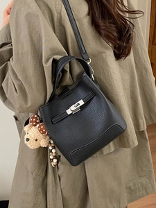 Minimalist black pebble leather bucket bag with silver twist lock and cute bear charm