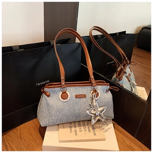 Détail du sac à bandoulière en denim avec bandoulière marron et breloque étoile argentée