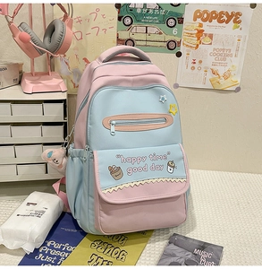 Detail of pink and blue color-block backpack with cute cartoon prints and plush pendant