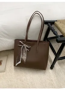 Detailed view of dark brown tote bag with textured leather and decorative silk scarf