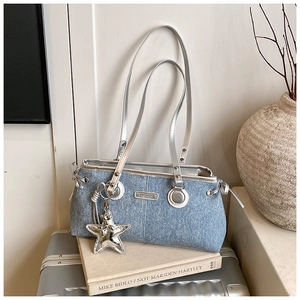 Détail du sac en jean bleu avec pendentif étoile argentée et plaque métal sur valise