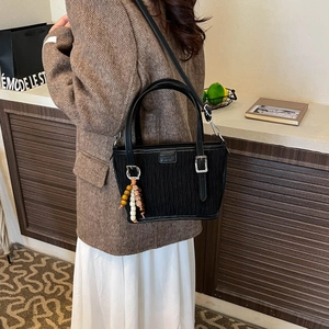 Detail of black bucket bag with pleated texture and colorful beads on a model