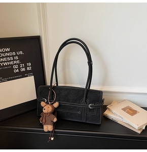 Detail of black tote bag with white contrast stitching and brown teddy bear charm