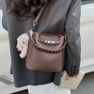 Détail du sac seau en cuir marron foncé avec poignée tressée et fermoir rotatif argenté