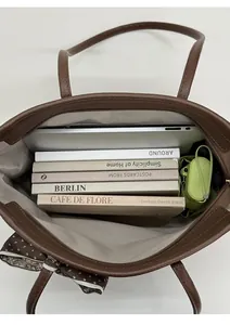 Detailed view of brown leather tote bag interior showing large capacity and silk ribbon