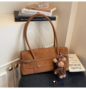 Detail of vintage brown suede shoulder bag featuring a cute teddy bear plush charm
