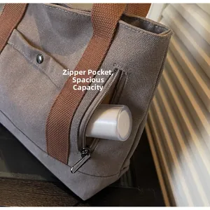 Detail of canvas tote bag showing outer zipper pocket and spacious interior capacity