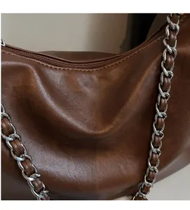 Detailed view of the soft textured brown leather and silver chain strap on a retro tote