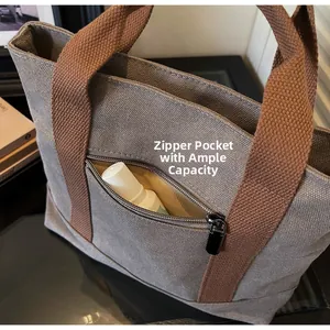 Detail of grey canvas tote bag featuring an external zipper pocket for easy storage