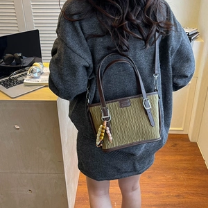 Olive green pleated bucket bag with brown leather handle and colorful bead charm