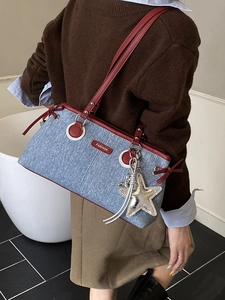 Sac bowling en denim bleu avec lanières en cuir rouge et breloque étoile sur l'épaule