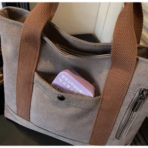 Detail view of durable canvas tote bag with front snap pocket and brown leather straps