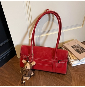 Detail of red faux suede shoulder bag with contrast stitching and a cute bear charm