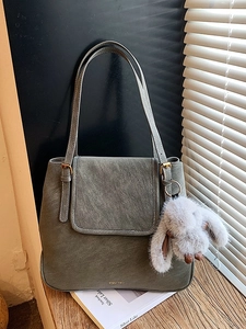 Vintage grey-green bucket tote bag with plush rabbit charm on a wooden table setup
