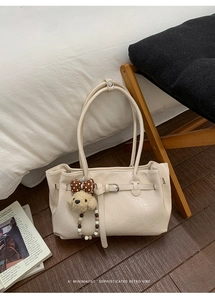 Dettaglio della borsa tote bianco crema con trama vintage e ciondolo a cucciolo