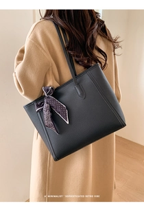 Detail of black pebbled leather tote bag with elegant polka dot silk scarf on the handle