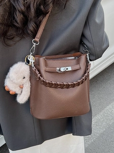 Sac seau en cuir marron avec poignée tressée et breloque lapin en peluche sur un mannequin