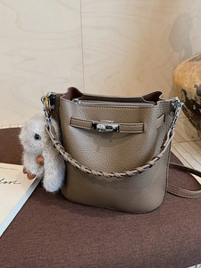 Sac seau élégant en cuir taupe avec fermoir rotatif et poignée en cuir tressé