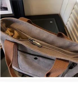 Close-up of smooth metal zipper and durable gray canvas texture on the tote bag