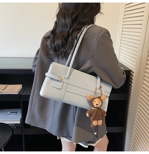 Light blue faux leather tote bag with teddy bear charm shown on model shoulder
