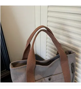 Detail of gray canvas tote bag with brown woven handle and sturdy metal zipper hardware
