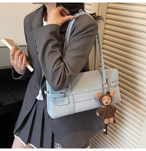 Detailed view of a light blue leather shoulder bag with a cute plush bear charm accessory