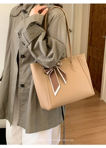 Minimalist light brown pebbled leather tote bag with a polka dot scarf on the handle