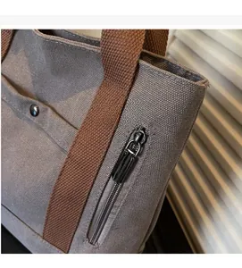 Detail of grey canvas tote bag featuring smooth metal zipper pocket and textured fabric