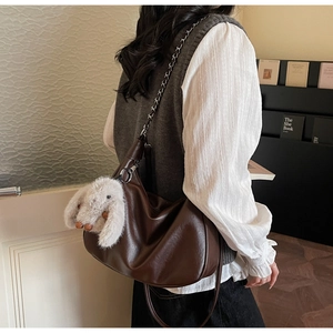 Detail of dark brown vintage leather hobo bag with silver chain strap and plush bunny charm