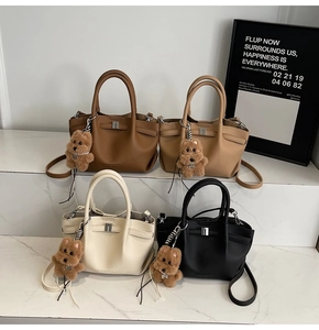 Gros plan de sacs seaux en cuir grainé de quatre couleurs avec breloques d'oursons