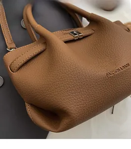 Détail du sac seau en cuir grainé marron avec fermoir rotatif en métal argenté et poignées