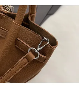 Détails du cuir grainé marron et des finitions métalliques argentées du sac seau