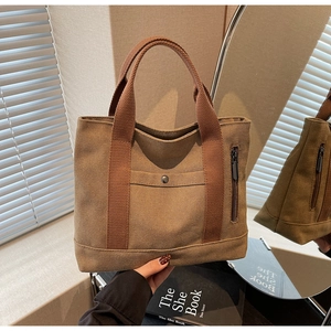 Detail of vintage brown canvas tote bag featuring metal snap pocket and sturdy handles