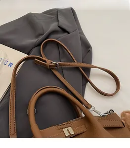 Détail d'un sac seau en cuir marron montrant le fermoir argenté et la bandoulière