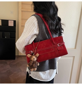 Detail of red faux leather shoulder bag with white contrast stitching and bear charm