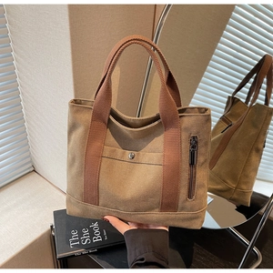 Detail of brown canvas tote bag with front snap pocket and vertical metal zipper