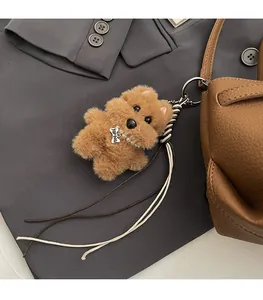 Détail d'un charme chien en peluche marron avec collier de perles sur un sac en cuir