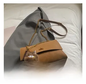 Detail of vintage brown suede tote bag with golden lock and fuzzy monster charm