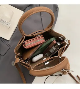 Sac seau en cuir marron montrant une grande capacité avec téléphone, portefeuille et cosmétiques